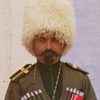 Thumbnail and detail of soldier in tall white fur hat and dressed in old fashioned dark green uniform, standing in front of a house and a yurt.