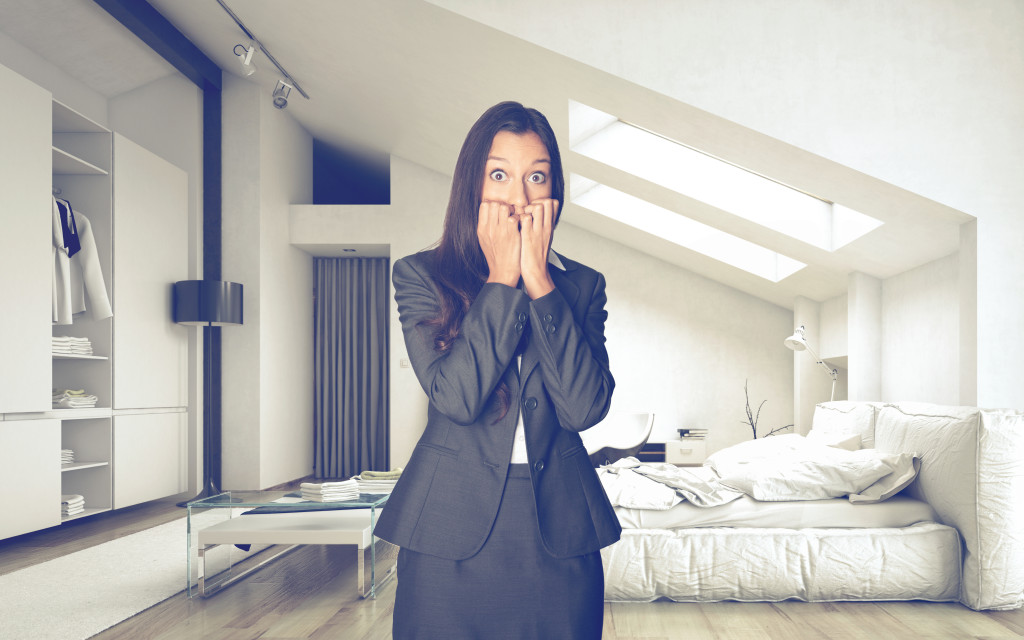 Young woman with shocked expression in white, fashionable and possibly rent-stabilized apartment. Copyright: PlusONE/Shutterstock.com