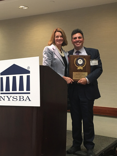 Emily Franchina poses with Richard Klass for a photo as he is awarded plaque for his service as Chair, New York State Bar Association, General Practice Section 2014-2015.