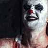 Somewhat frightening staged photo of a man with clown makeup, sitting on the ground, holding a hatchet, with blood on his shirt. Illustrates a case study about an order of attachment
