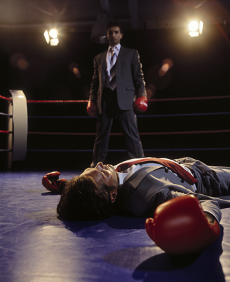 Two men in business suits in boxing ring, one unconscious on the mat, one standing. Illustrating article by Richard Klass about ejectment of a boxing gym.
