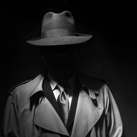 Man posing in the dark with a fedora hat and a trench coat, 1950s noir film style character. Image used to illustrate an article by Richard Klass involving the Doctrine of Res Judicata.