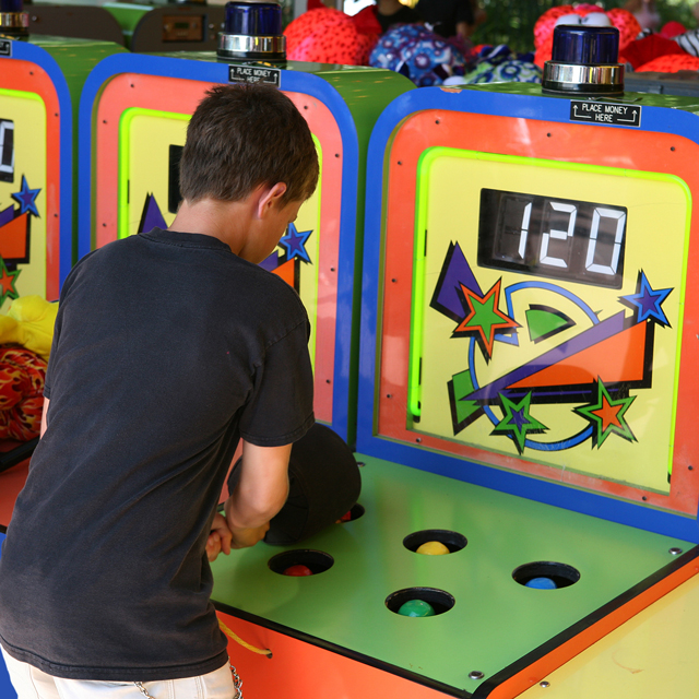 Boy holding a large soft club in hand, playing a colorful arcade game called Whac-a-mole, illustrating an article by Richard Klass about litigation.