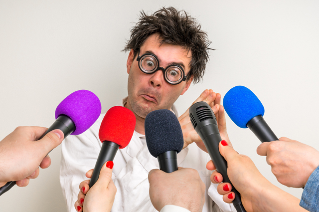 Man with exaggerated round glasses and messy hair, dressed in white coat, with hands holding a range of microphones towards his mouth. Illustrating article about expert witnesses for Richard Klass, attorney, New York